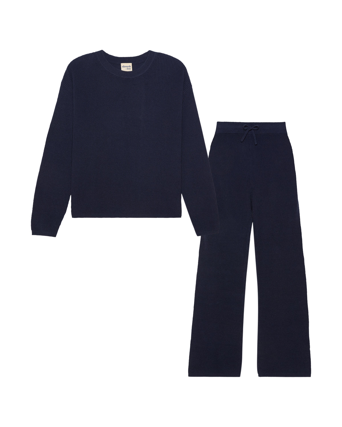 A two-piece knit loungewear set in a navy blue color, featuring a long-sleeve crewneck top and matching wide-leg pants with a drawstring waist, displayed on a solid white background. Adeline Knit Set in Sand by Ellsworth + Ivey.