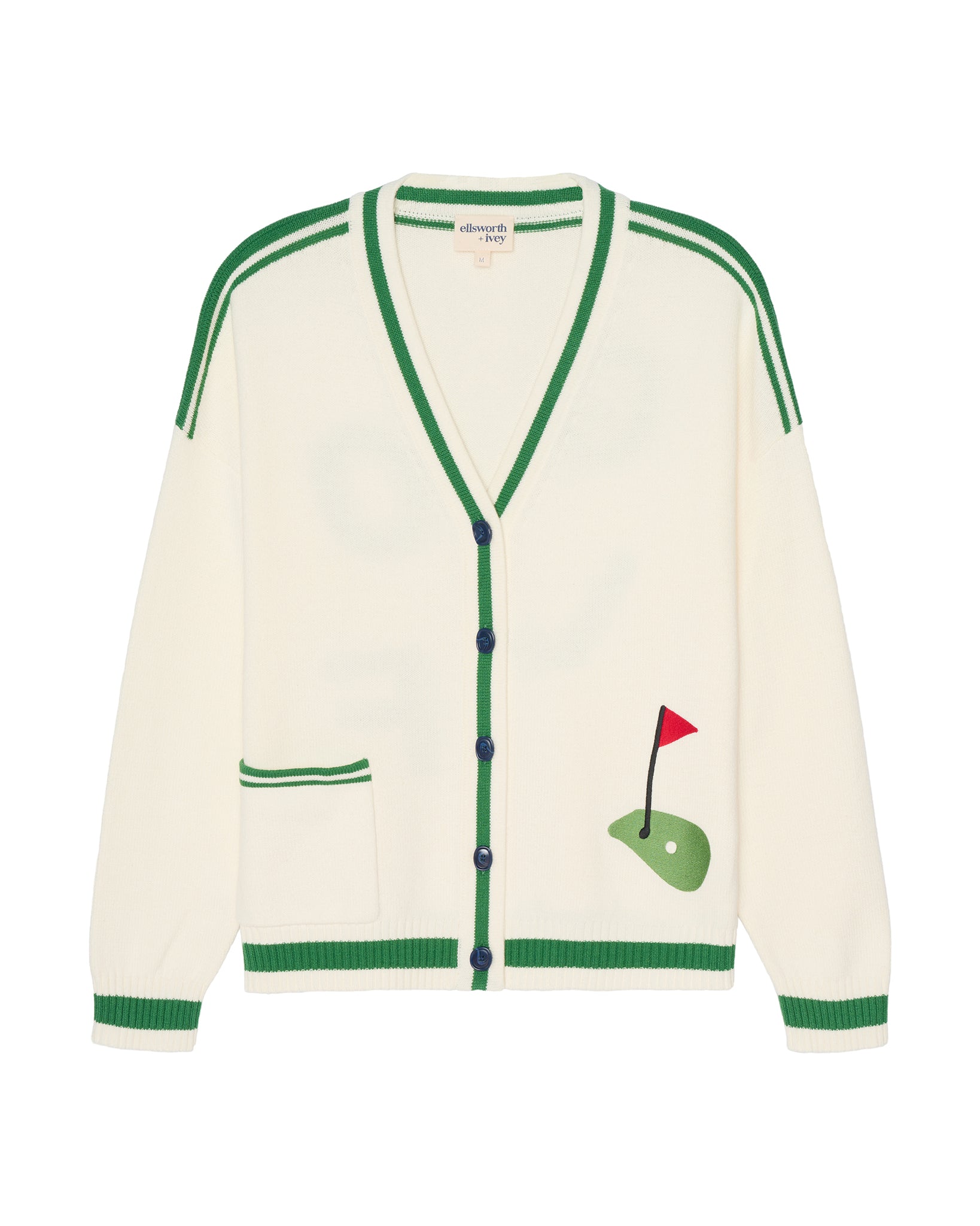 An ivory off-white knit cardigan women's golf sweater with green trim, featuring a golf-themed graphic on the lower right front pocket depicting a green putting green with a red flag. Emily Varsity Cardigan - Golf by Ellsworth + Ivey.