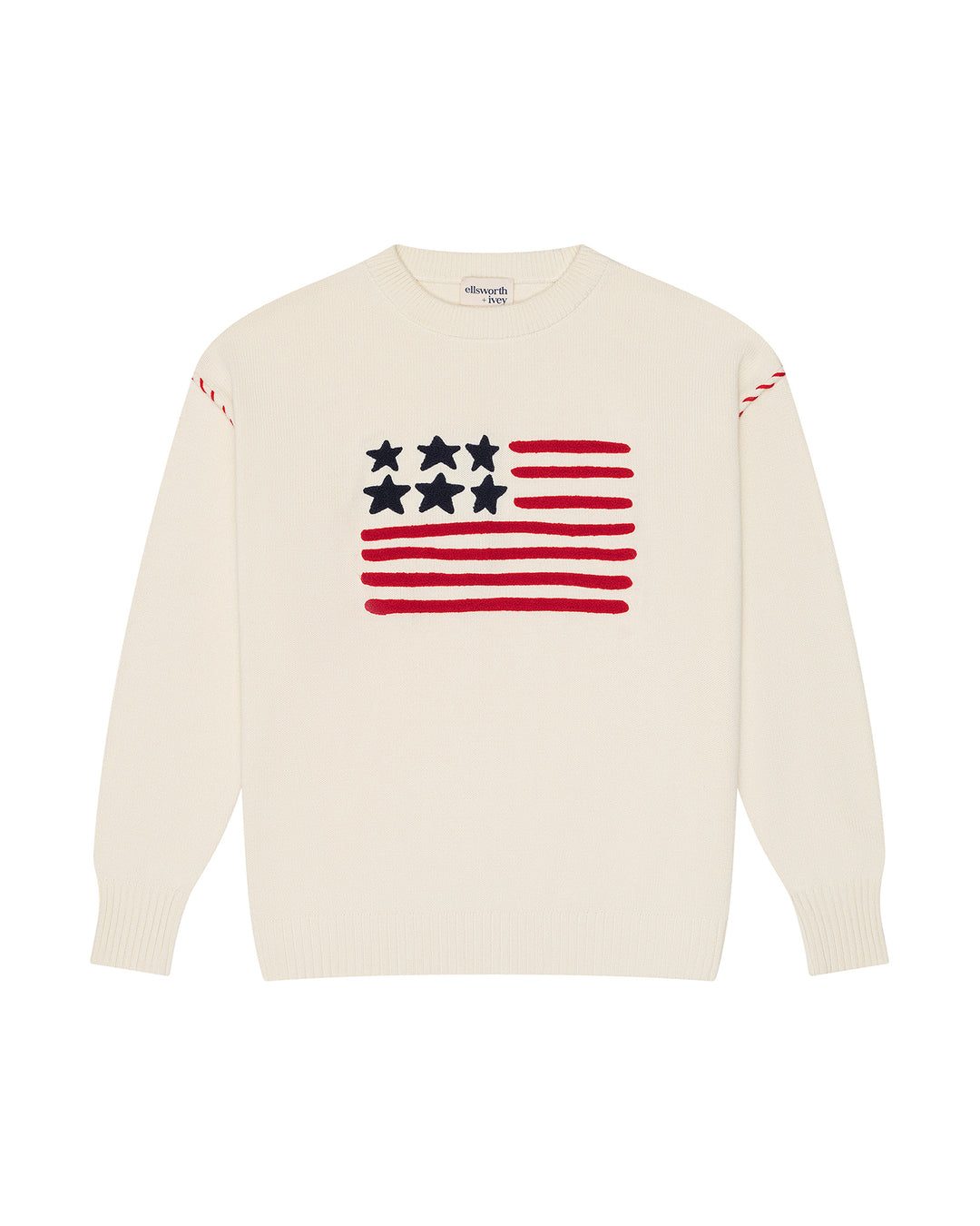 An ivory off-white crewneck women's sweater featuring a knitted American flag graphic on the chest, with red stripes, white stars, and red stripe details on the shoulders, shown against a plain white background. Riley Crew - American Flag by Ellsworth + Ivey.