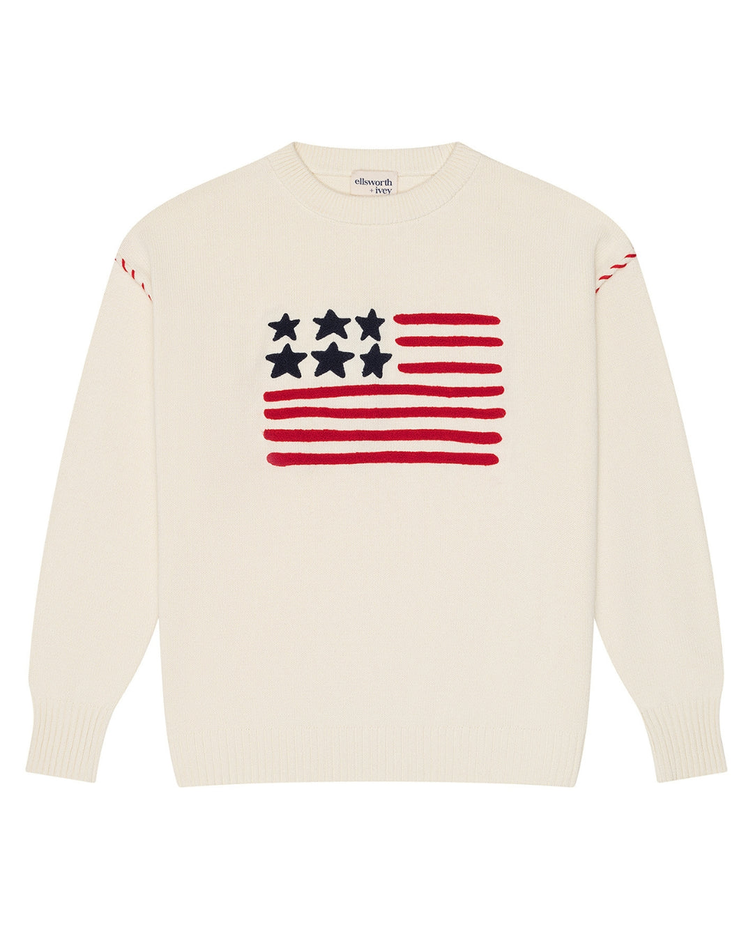 An ivory off-white crewneck women's sweater featuring a knitted American flag graphic on the chest, with red stripes, white stars, and red stripe details on the shoulders, shown against a plain white background. Riley Crew - American Flag by Ellsworth + Ivey.