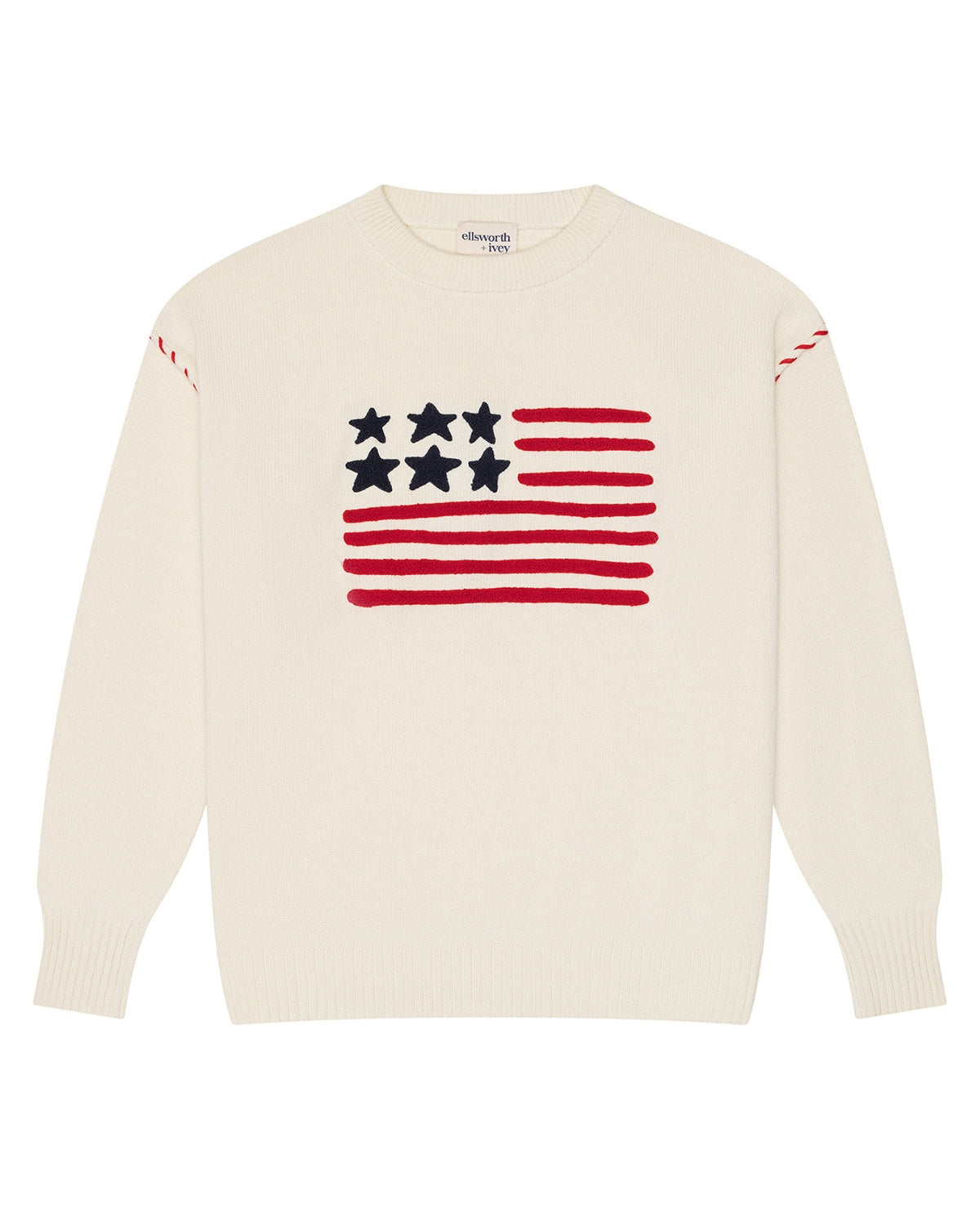 An ivory off-white crewneck women's sweater featuring a knitted American flag graphic on the chest, with red stripes, white stars, and red stripe details on the shoulders, shown against a plain white background. Riley Crew - American Flag by Ellsworth + Ivey.
