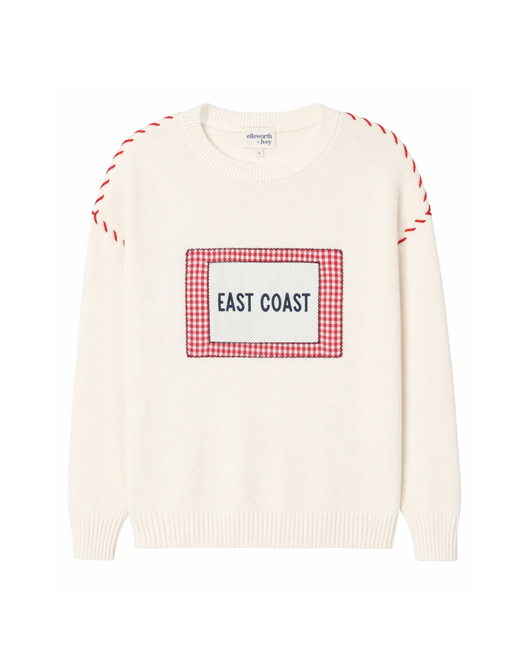 An off-white knit sweater with a red and white gingham graphic on the chest that reads 'EAST COAST' in navy text. The sleeves feature red and white whip stitch details near the shoulders, all shown against a plain white background.  Ellsworth + Ivey Riley Crew - East Coast.