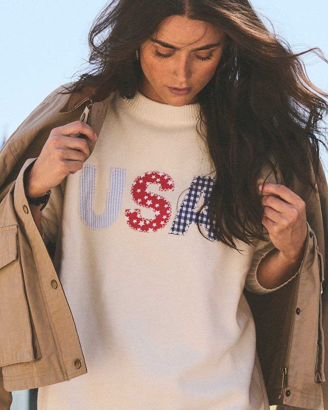 A woman wearing an ivory cream knit oversized crewneck sweater with a patriotic &