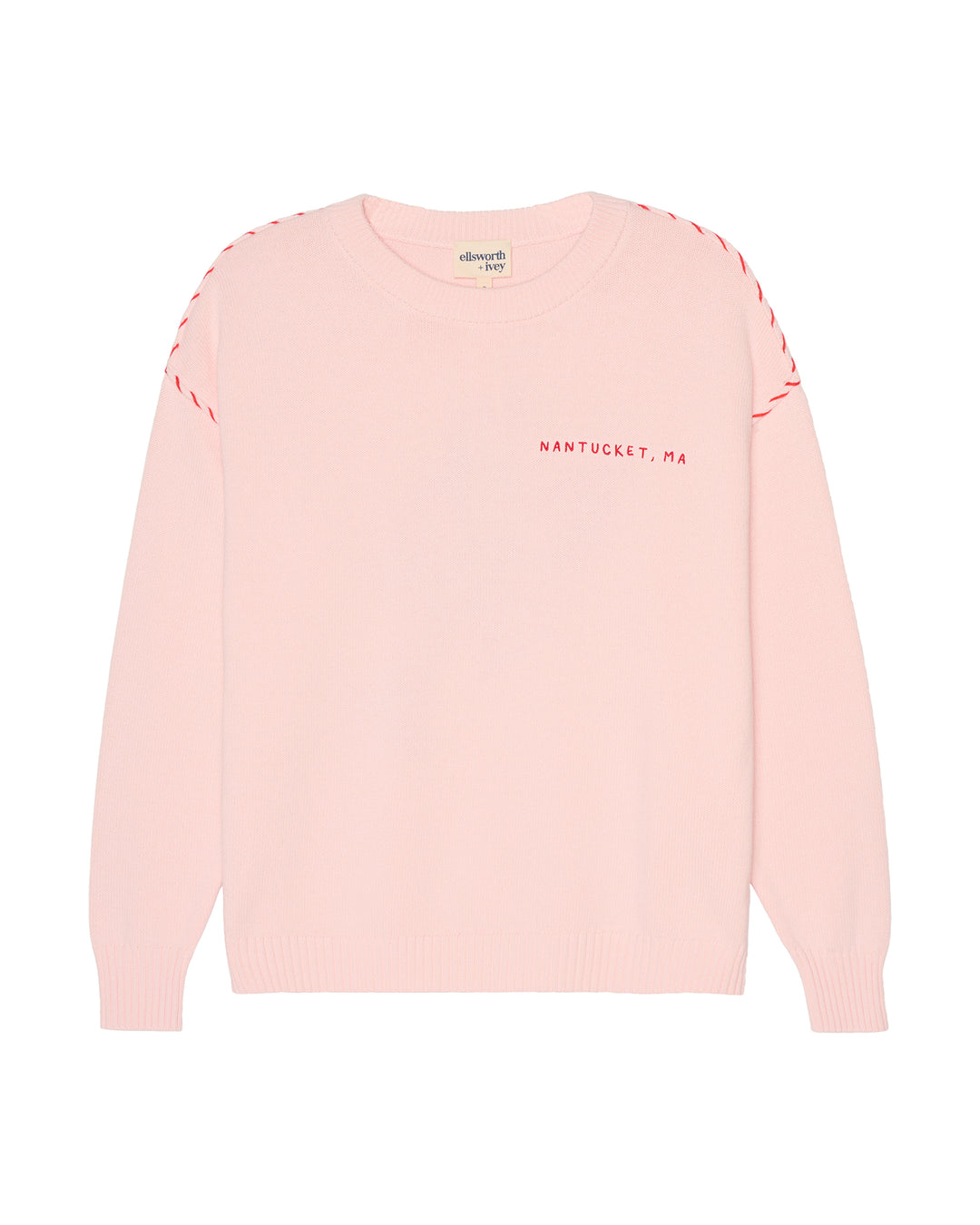 A light pink crewneck sweater with red dashed stitching along the shoulders and red text reading &