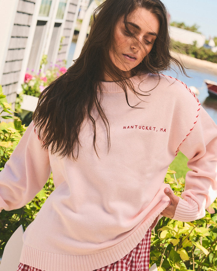 A woman wearing a light pink oversized crewneck sweatshirt with &