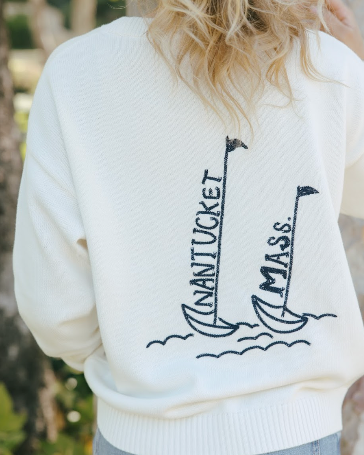 Ivory white oversized sweatshirt with 'Nantucket Mass.' design on the back, worn by a woman outdoors. Riley Crew Sweater - ACK Sailing by Ellsworth + Ivey.