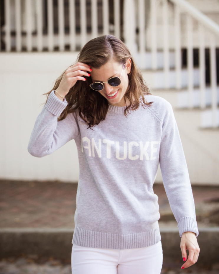 Women wearing a grey sweater with white 'Nantucket' across the chest, outside. Classic Crew Sweater- Nantucket by Ellsworth + Ivey.