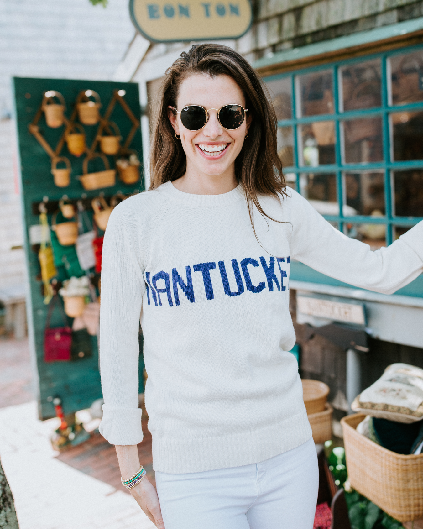 Women wearing a ivory white sweater with blue 'Nantucket' across the chest, outside. Classic Crew Sweater- Nantucket by Ellsworth + Ivey.
